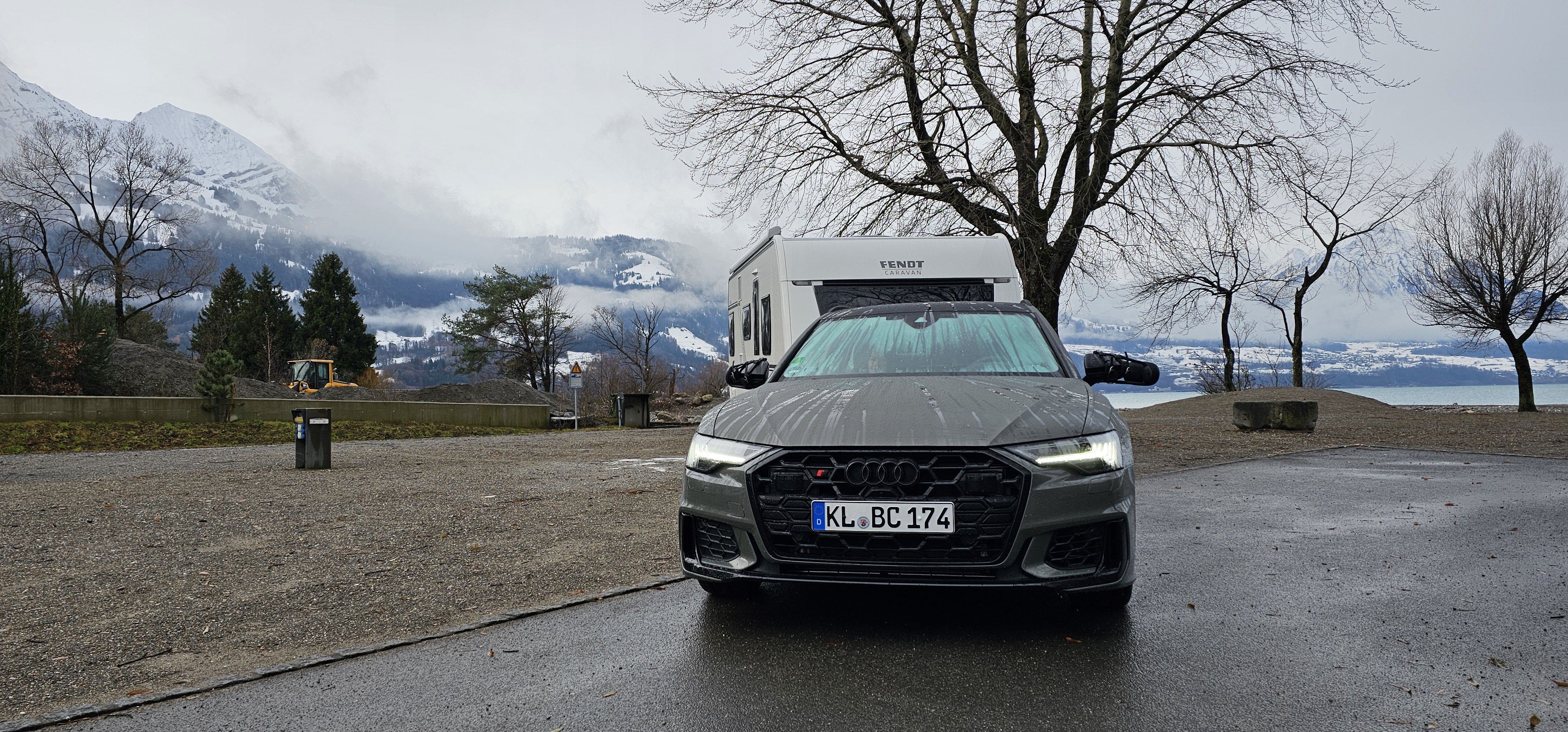 Audi A6 wagon and Fendt caravan parked at Manor Farm 1, Lake Thun and clouded Bernese Alps behind