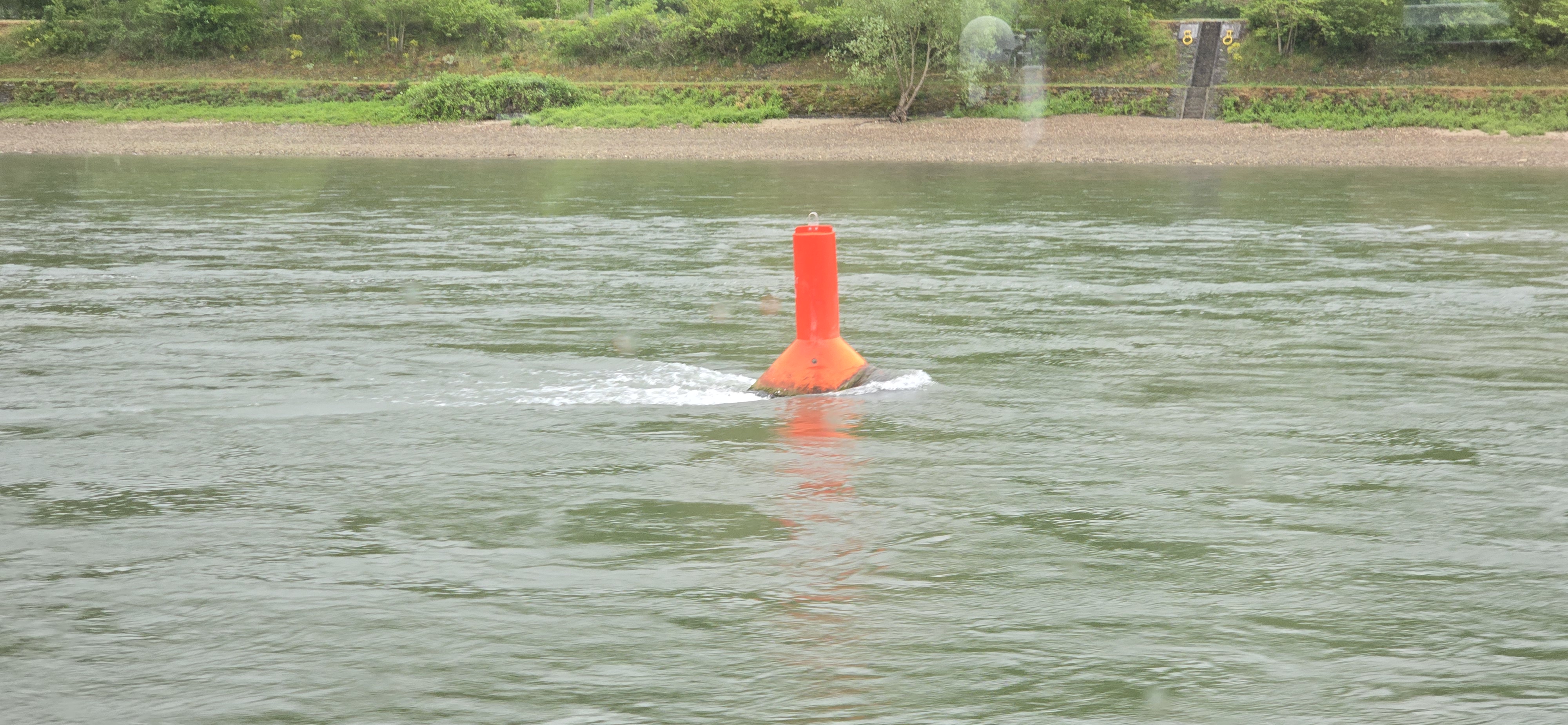Orange Rhine navigation buoy in the river current as the cruise boat departs St. Goar