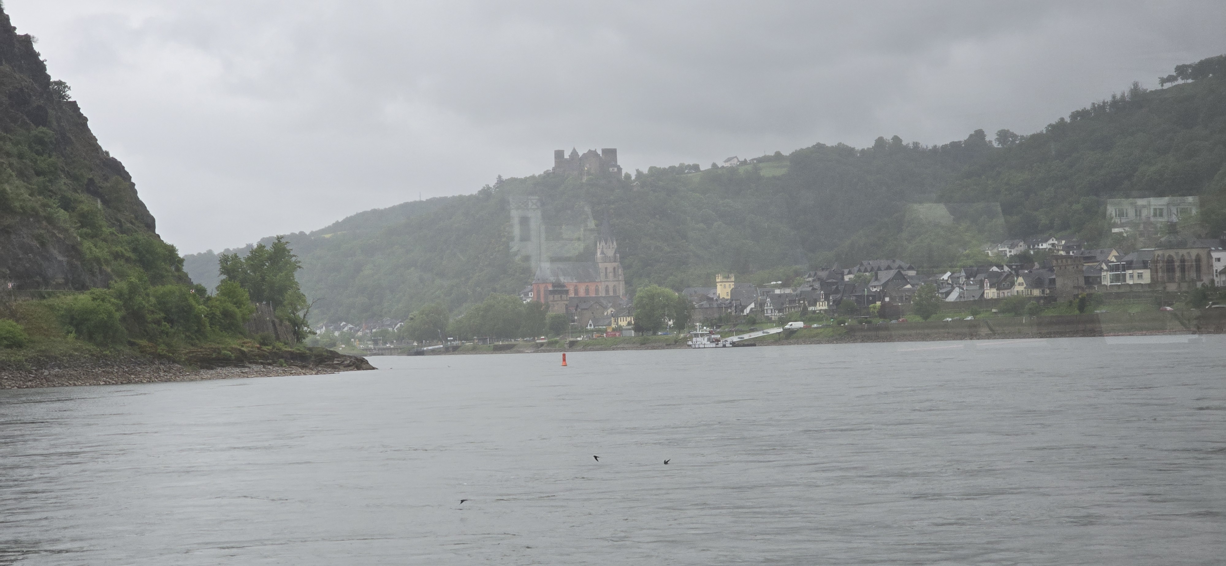 Oberwesel and Burg Schonburg on the ridge above the town, seen from the KD cruise vessel in misty rain