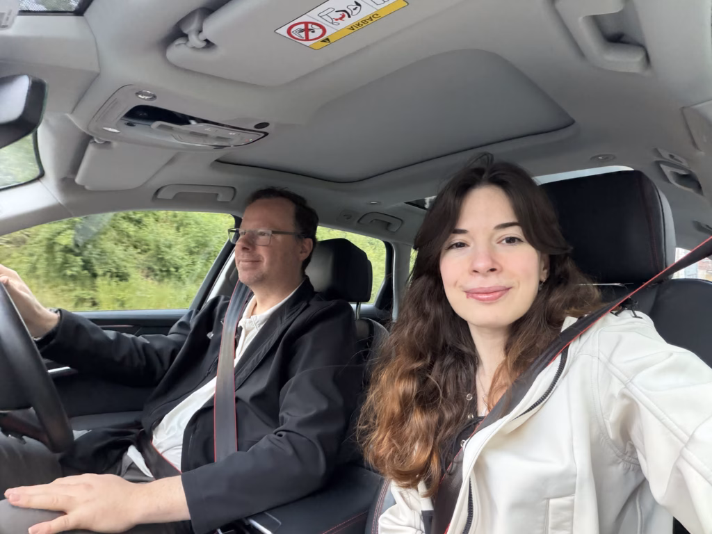 Ryan driving and Samira in the passenger seat, both buckled in for an early-morning car selfie at the start of the day