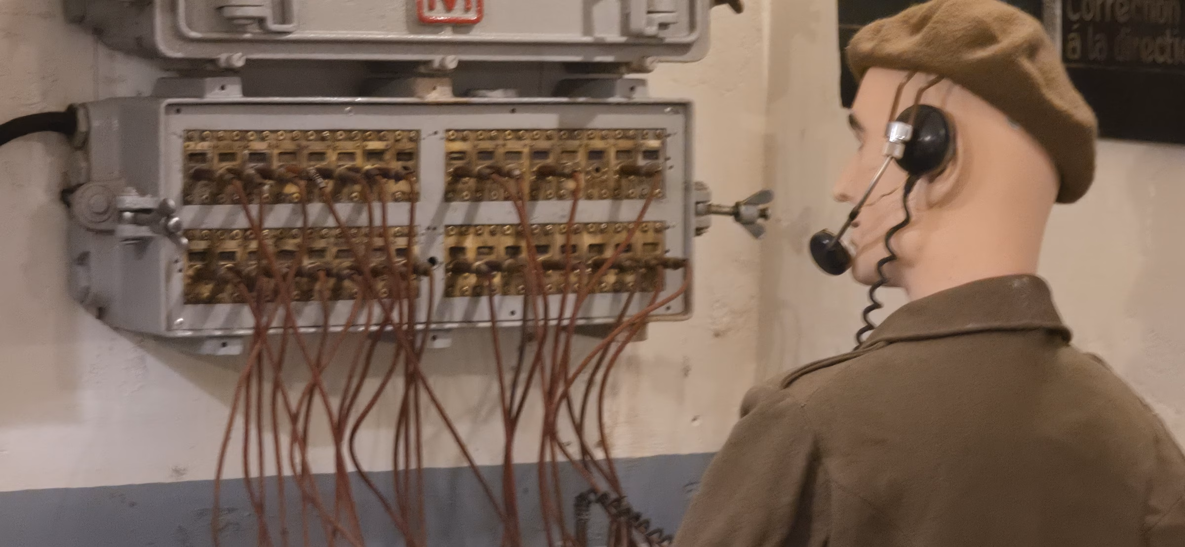 Mannequin of a French communication soldier in beret and headset operating a brass switchboard with red wires in the underground command post at Fort Schoenenbourg