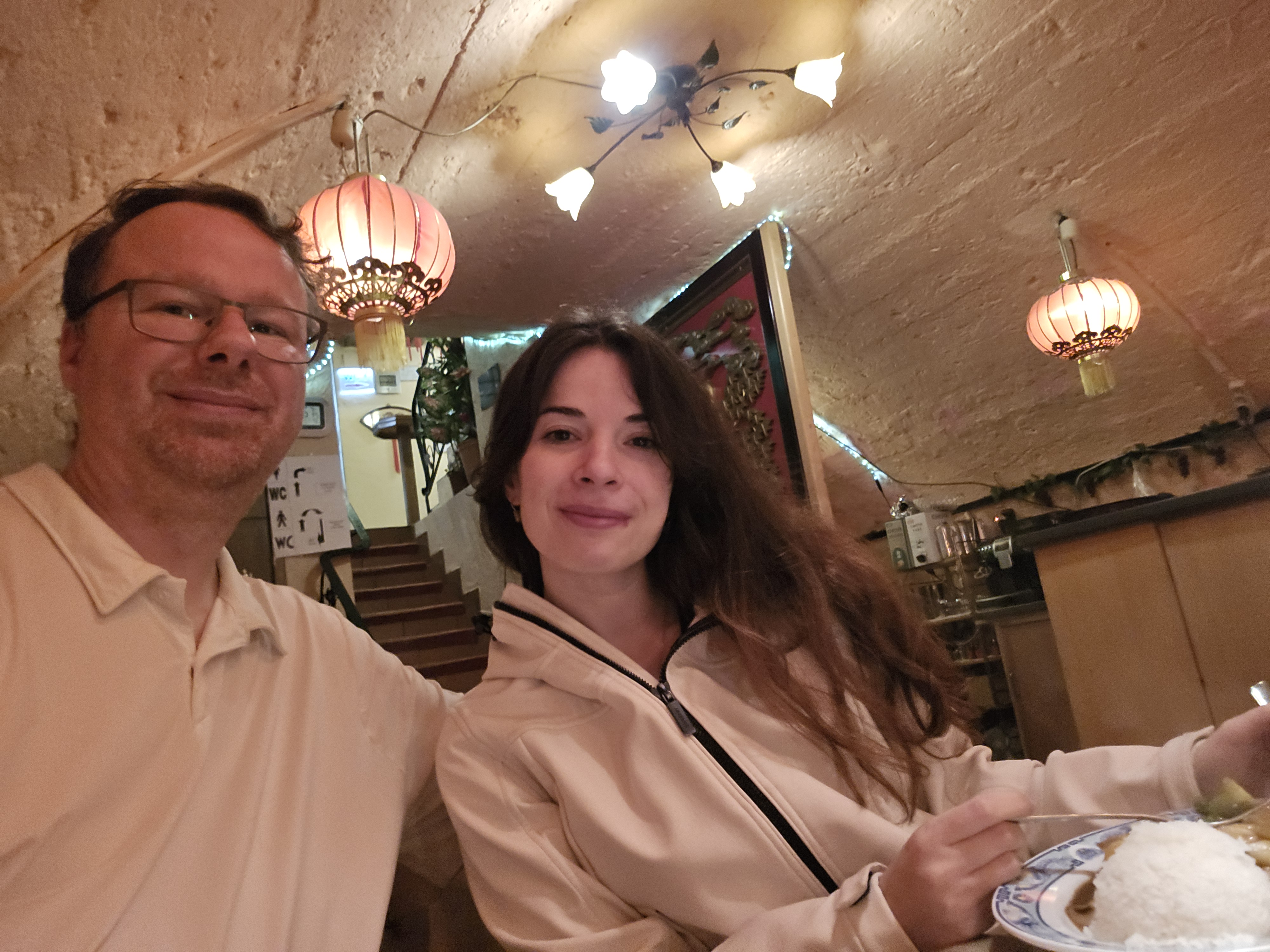 Asia Kim vaulted cellar dining room with Chinese lanterns, stone ceiling, and staircase to street