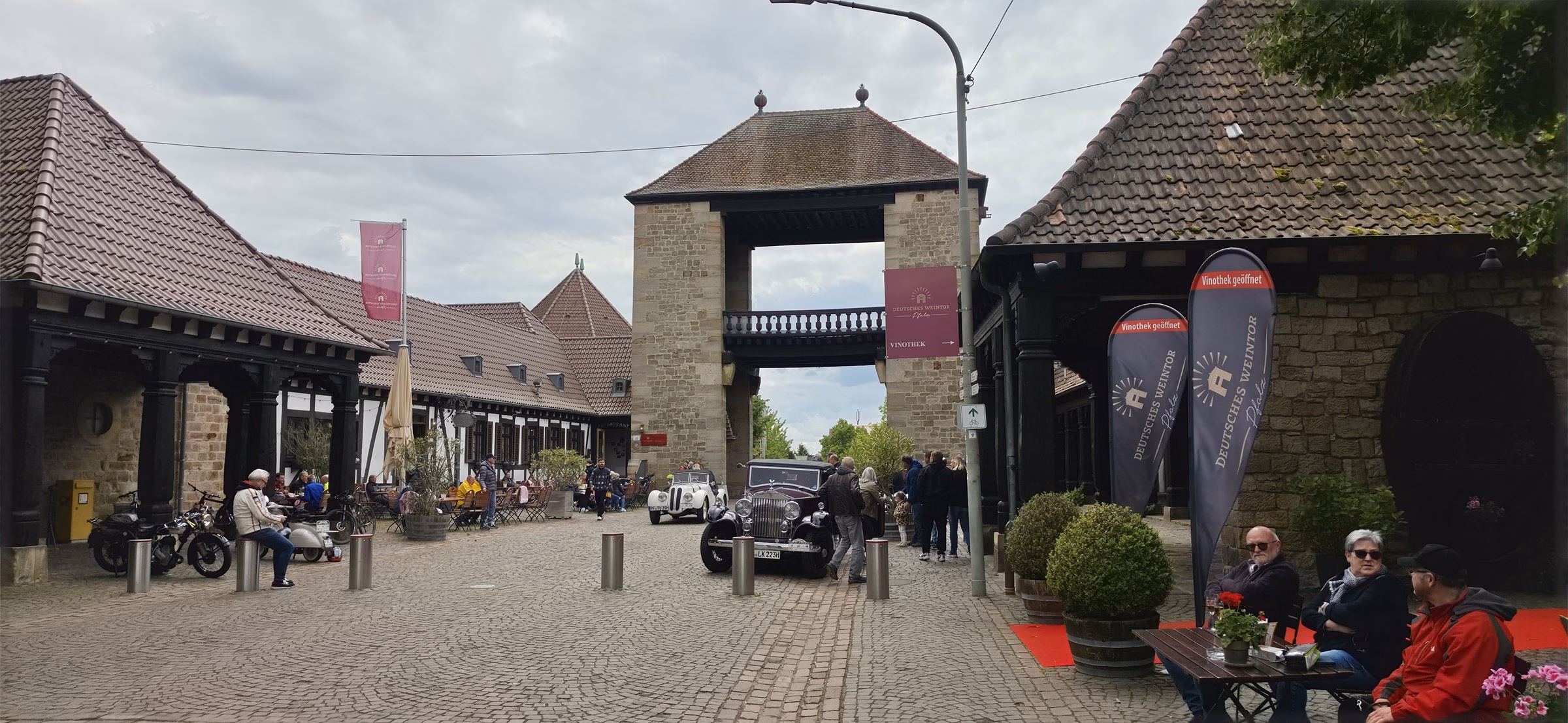 Inside the Deutsches Weintor courtyard on a Deutsches Weintor day trip with classic-car-meet banners visible on the arch