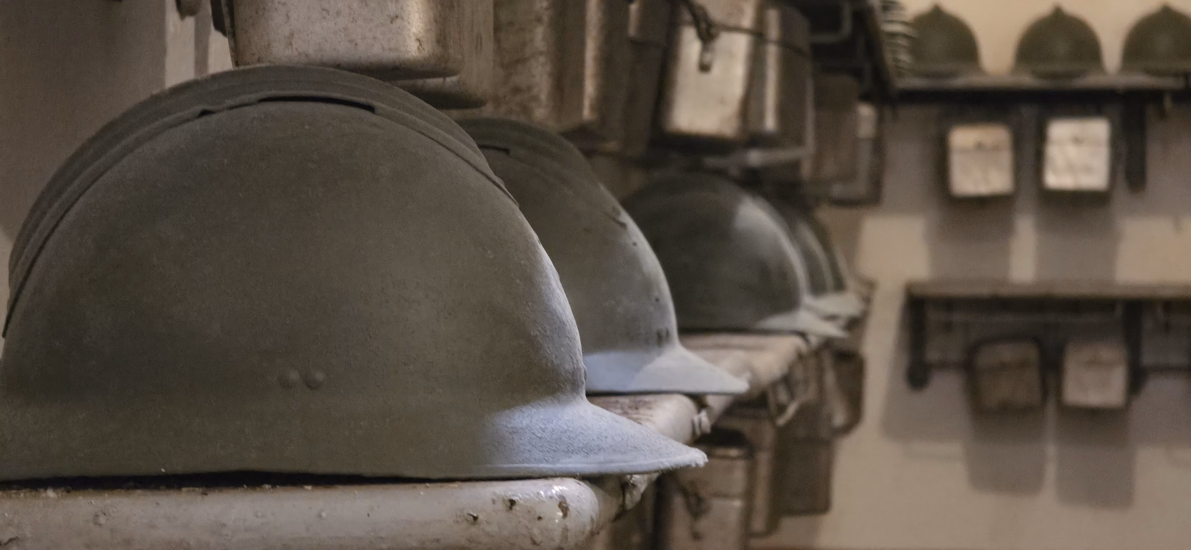 Row of 1930s French Adrian-pattern infantry helmets on a display shelf inside Fort Schoenenbourg