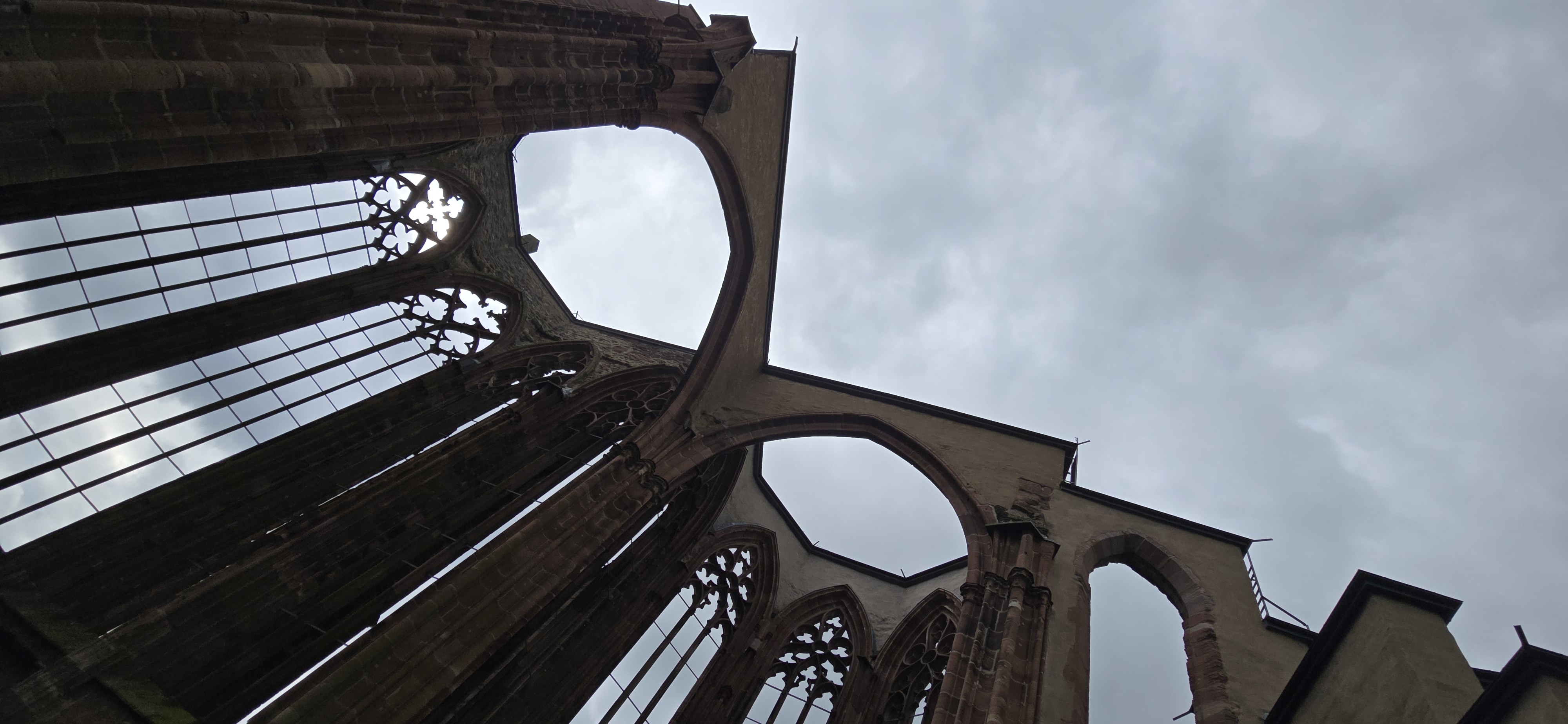 Wernerkapelle Gothic tracery viewed from inside the ruin, roofless arched windows framing overcast May sky above Bacharach