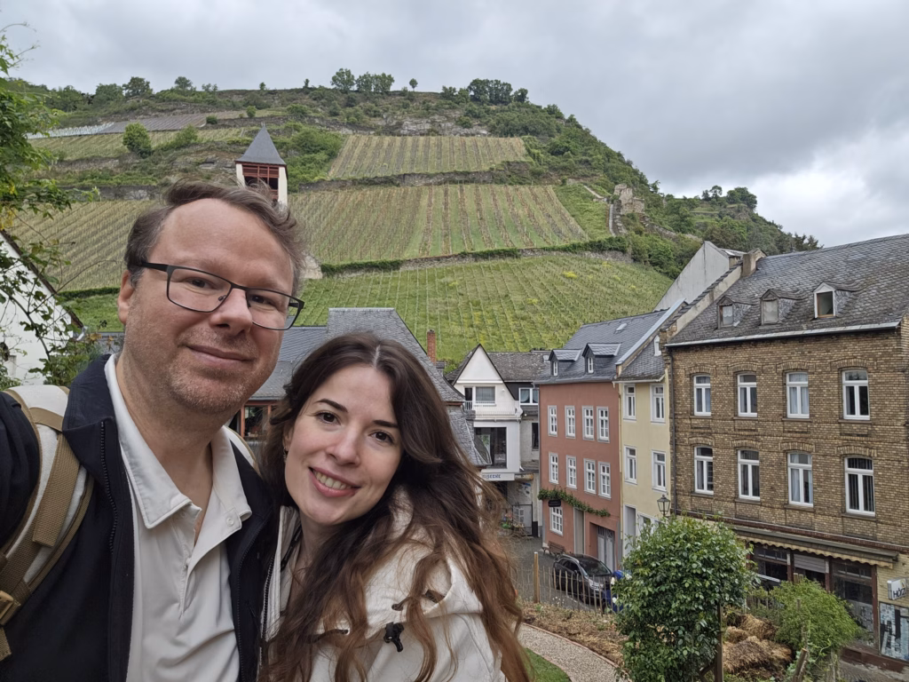 Ryan and Samira taking a selfie with Bacharach rooftops and terraced vineyards on the hillside behind