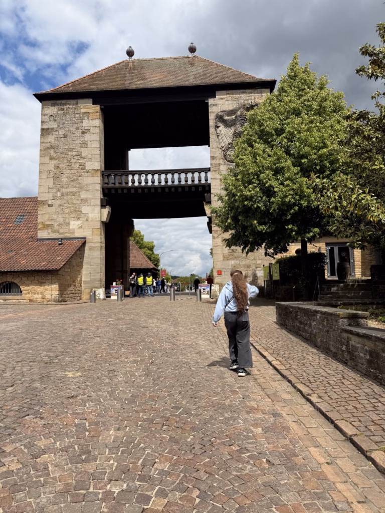 The 1936 Deutsches Weintor arch from the cobbled approach with a relief carving on the right pillar and a person walking toward it