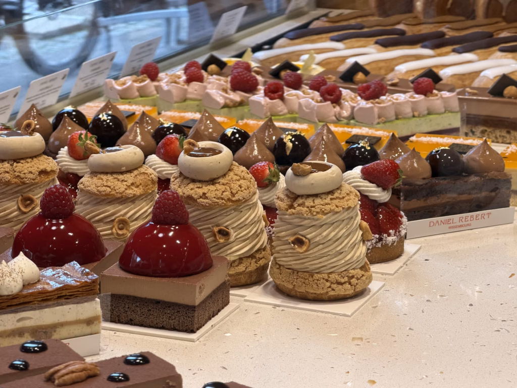 Rows of French pastries in the Daniel Rebert display case: chestnut-cream Mont-Blancs, glossy raspberry domes and chocolate tartlets