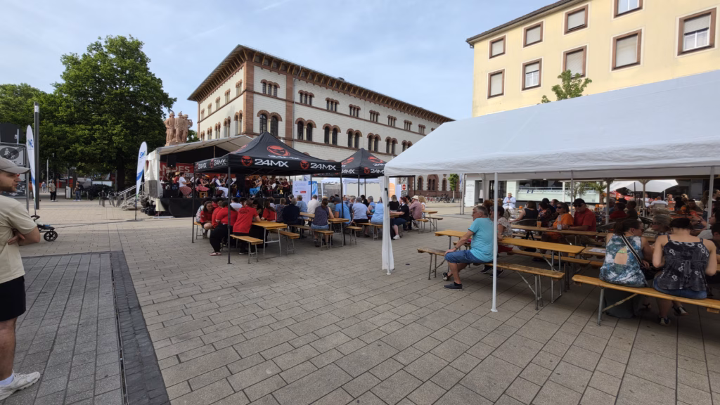 Stiftsplatz set up for the Kaiserslautern 750 anniversary programme: event tents, Bierbänke, and a sponsor-banner stage on the historic square, May 2026