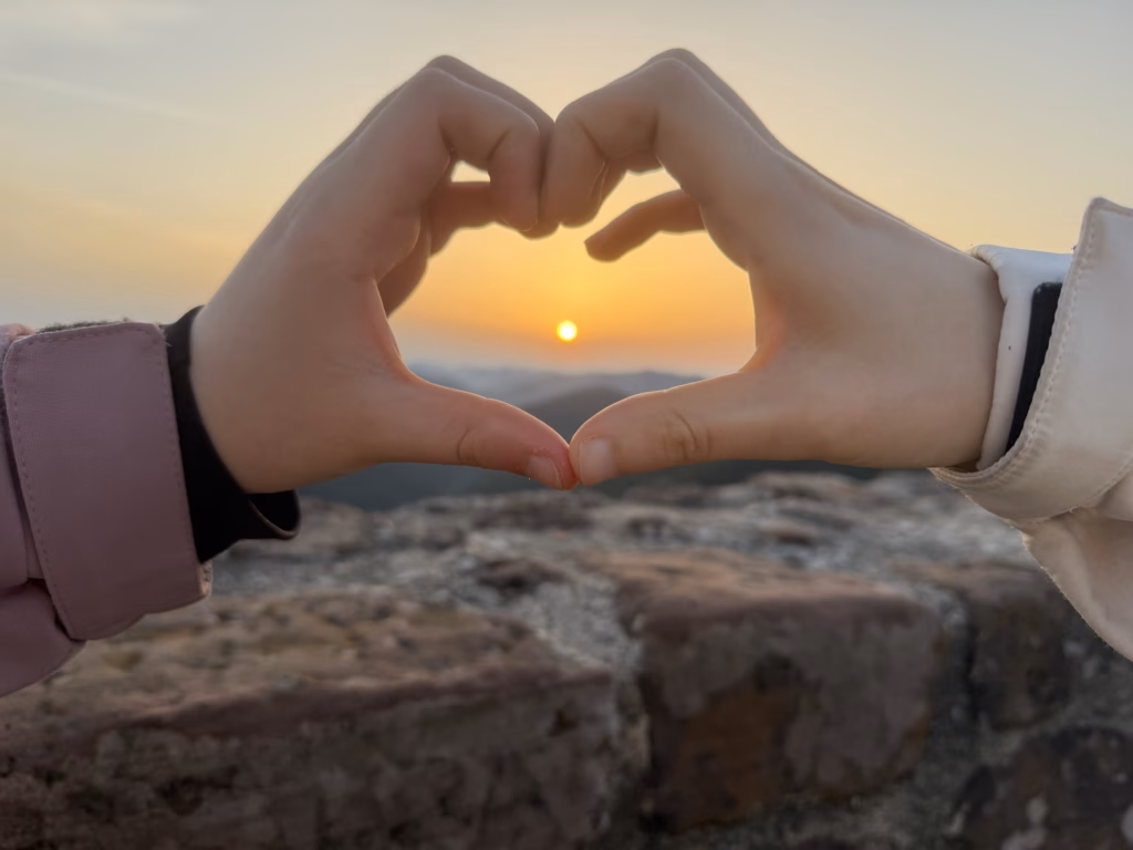 Lulu and Samira making heart-hands around the rising sun over the Wasgau